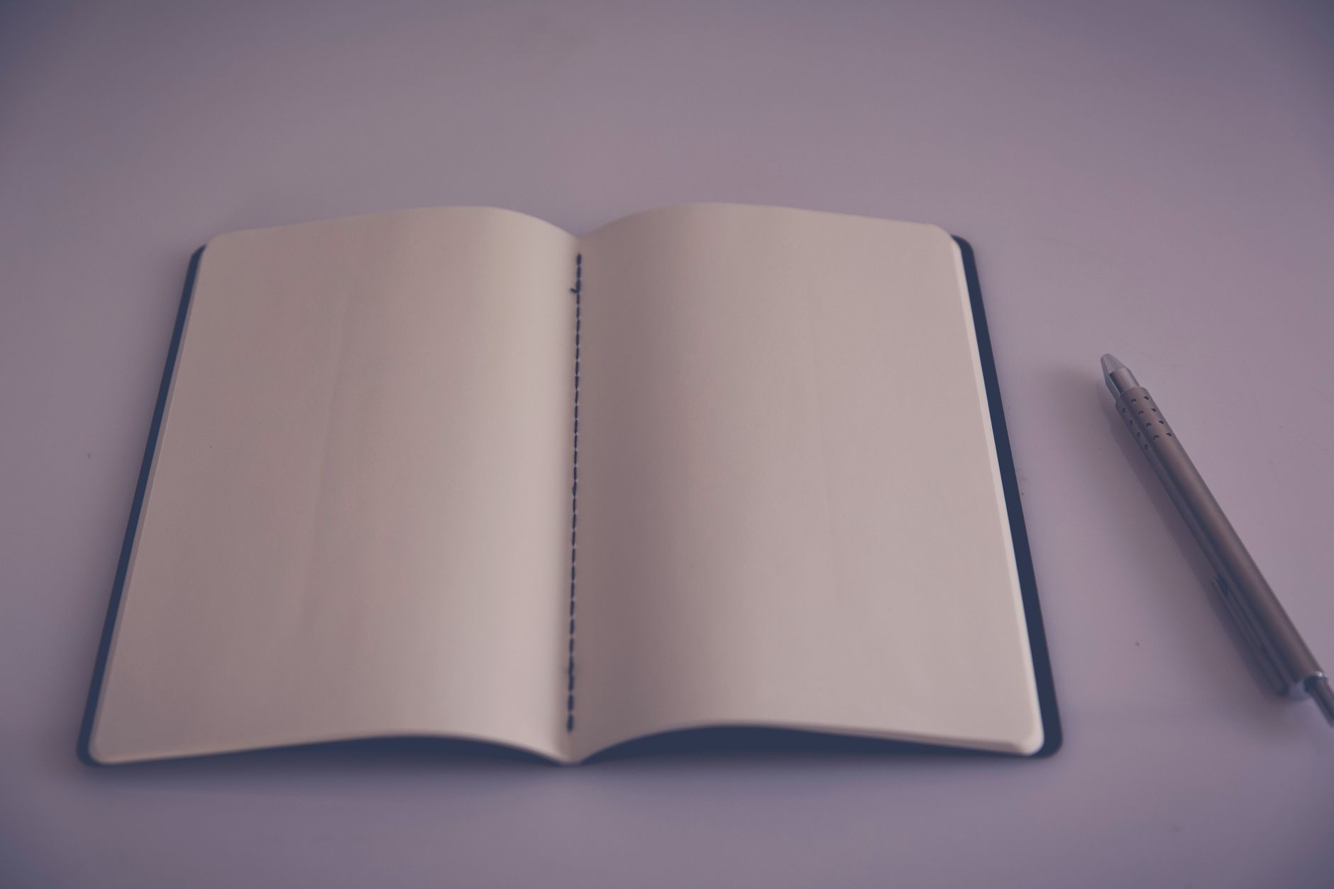 Carnet ouvert sur une page blanche avec un stylo