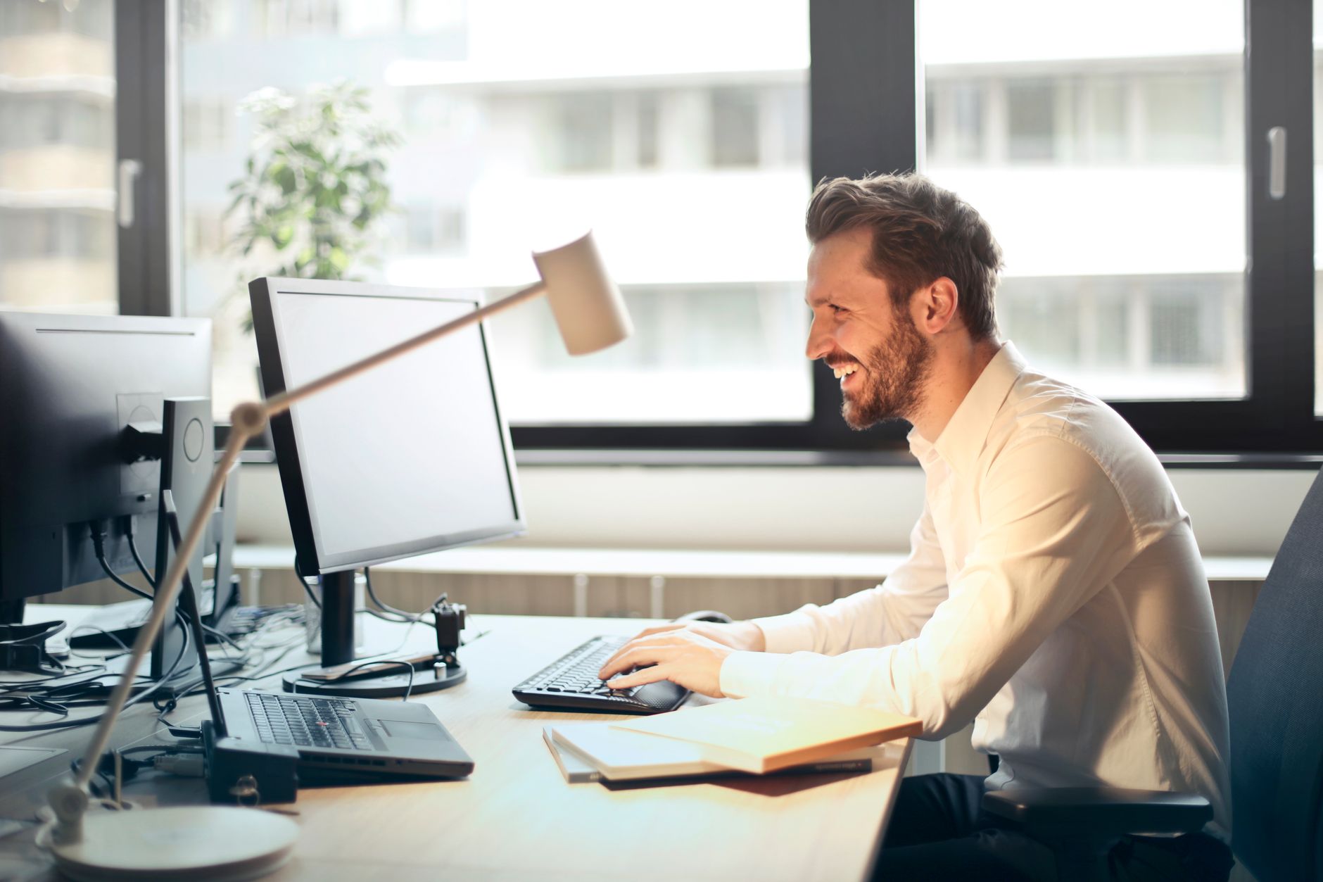 Homme souriant à son poste de travail près d’une fenêtre